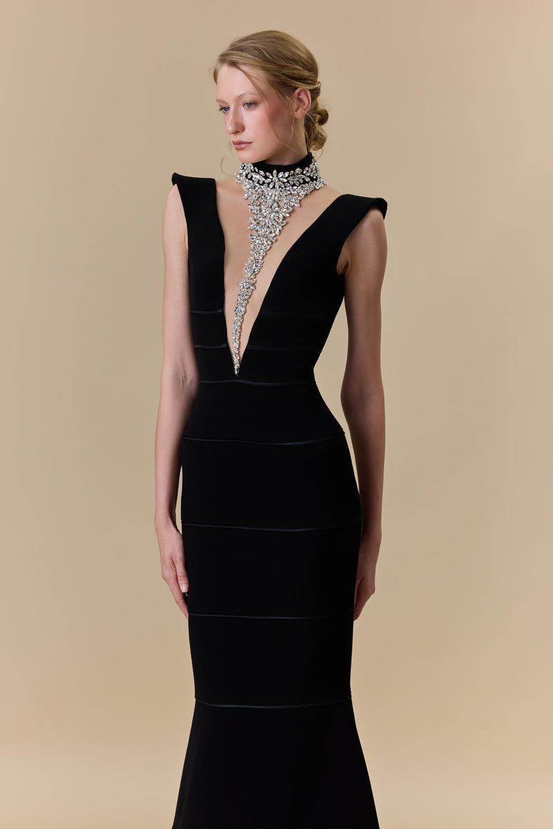 A crêpe fitted dress with a deep V neckline and horizontal radzimir detailing along the silhouette.