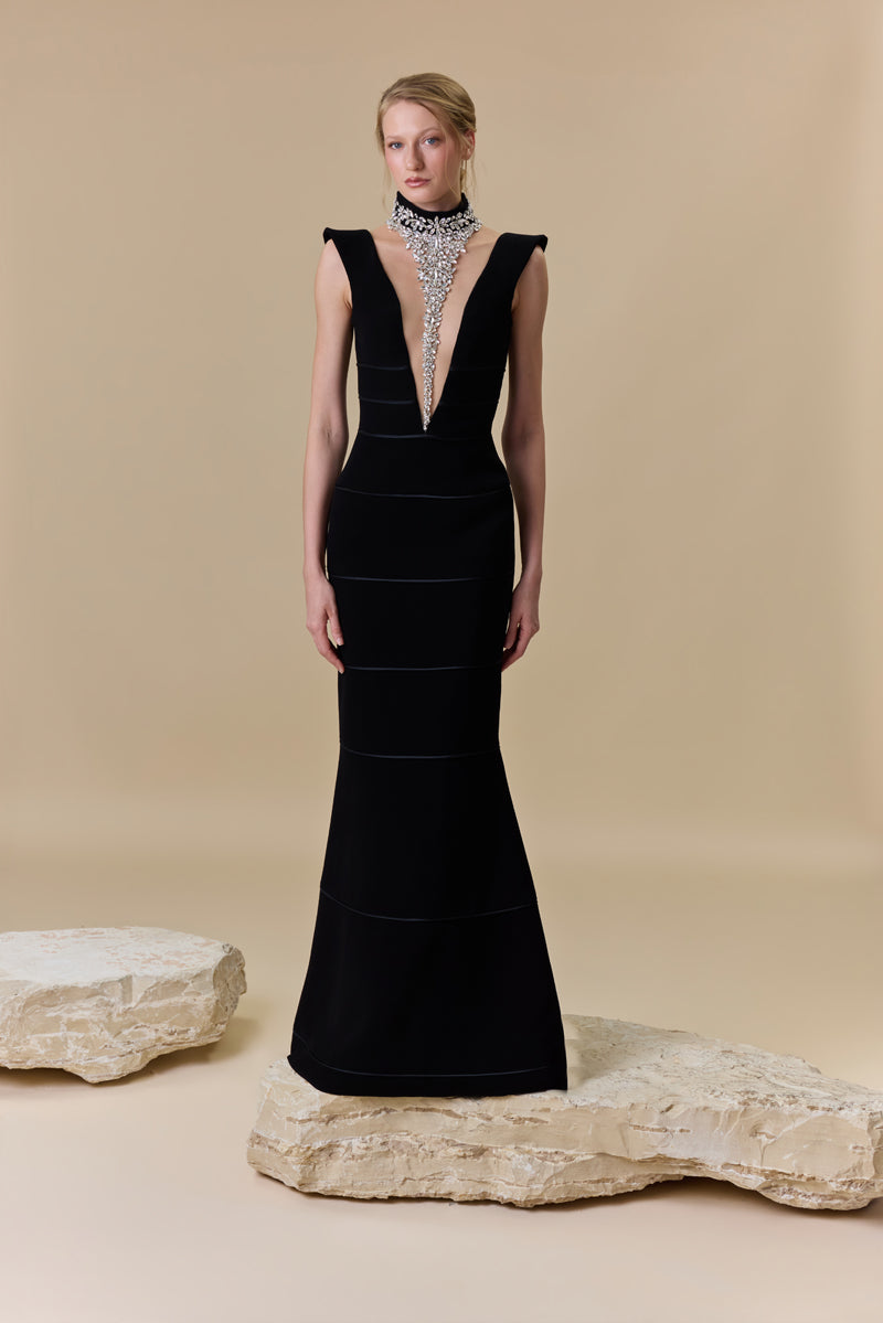 A crêpe fitted dress with a deep V neckline and horizontal radzimir detailing along the silhouette.