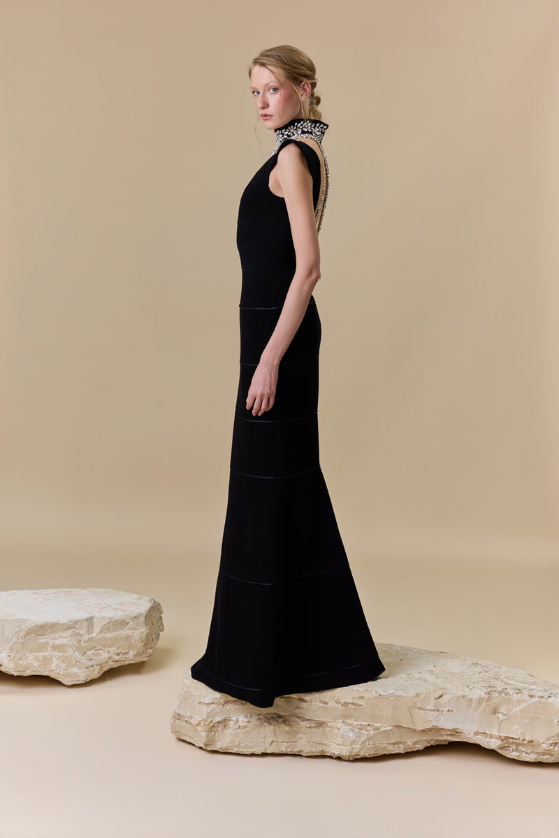 A crêpe fitted dress with a deep V neckline and horizontal radzimir detailing along the silhouette.