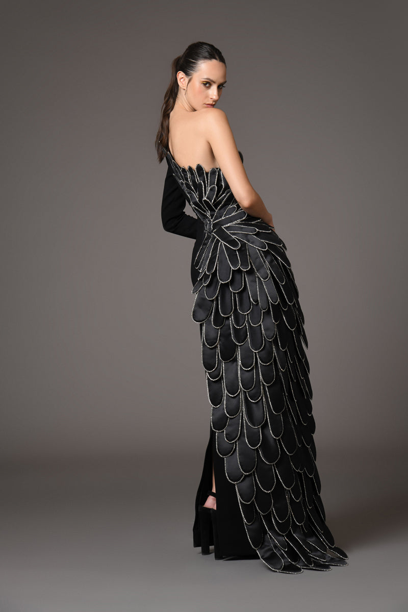 A sculpted gown in black crepe paired with a winged cape of layered hand-crafted plumes in scuba and crystals side