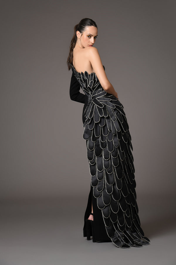 A sculpted gown in black silk crêpe paired with a winged cape of layered 3D hand-crafted plumes in scuba and crystals