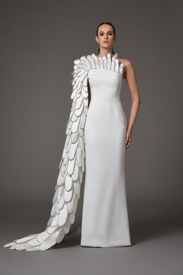 A sculpted gown in white silk scuba paired with layers of 3D hand-crafted plumes emerging from the bust into a cape