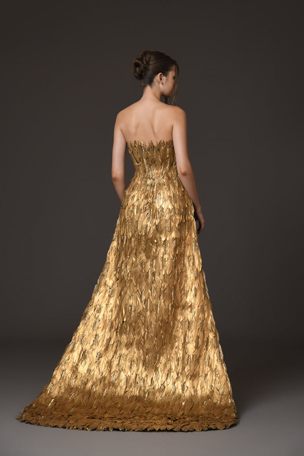 A golden feather corseted bustier with a dramatic overskirt, paired with a silk black crêpe skirt