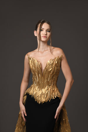 A golden feather corseted bustier with a dramatic overskirt, paired with a silk black crêpe skirt