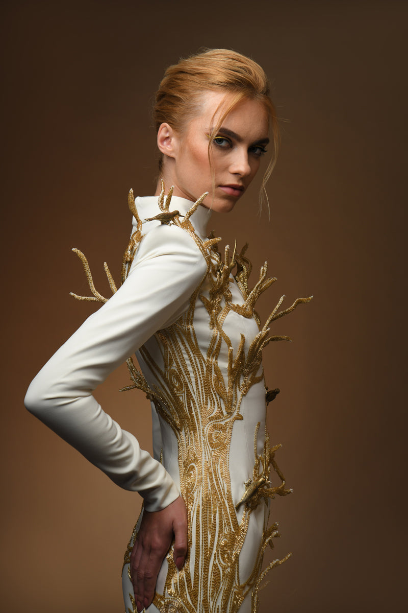 side view white crepe dress with golden tree and branches coming out of it and brass birds long sleeve close up