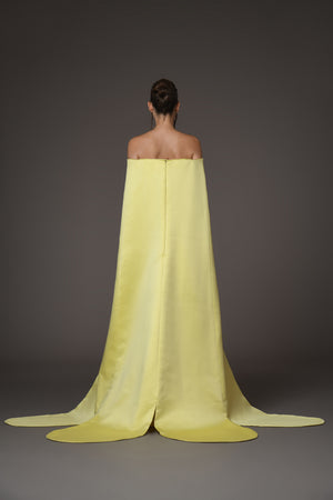 A corseted yellow gown featuring a cape and sunflower crystal buttons details