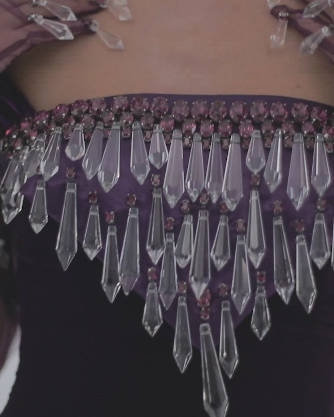 Sleeveless purple velvet strapless gown, hand embroidered with Swarovski stones, crystal spikes, and finished with coq plumes. Worn with tulle gloves embroidered with stones and dripping crystals