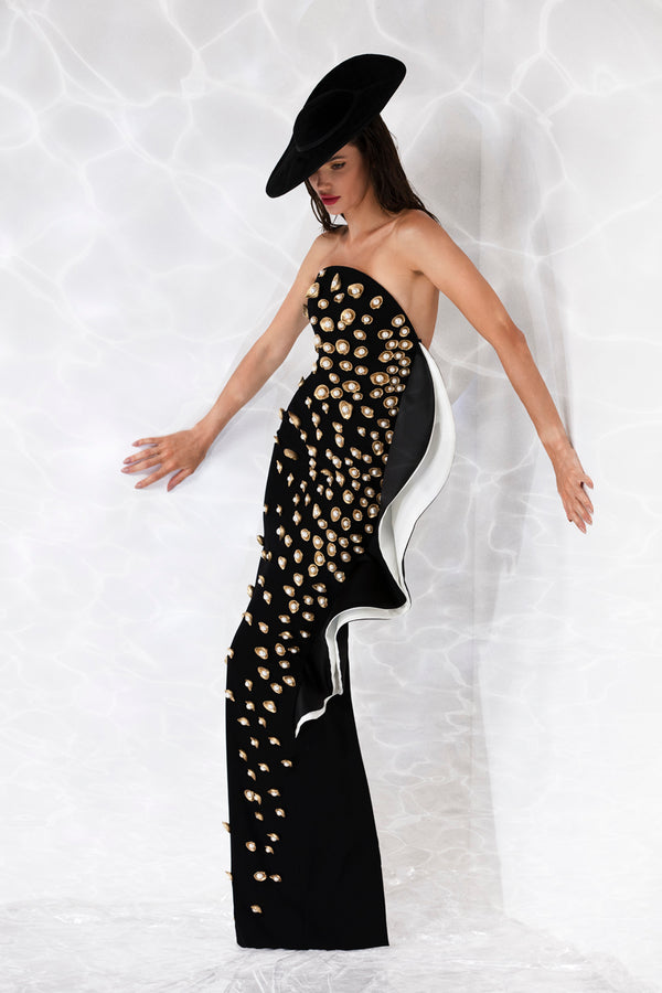 Strapless corseted black crêpe column gown with an exploded ruffle, embroidered with pearls and gold hand-painted scallop shells
