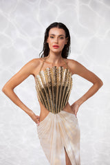 Off-the-shoulder gold-plated scallop shell corset handcrafted from solid brass and studded with crystals, worn with a draped skirt in gold foiled silk tulle