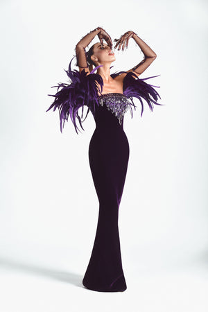 Stones and dripping crystals embroidered purple velvet strapless gown, hand embroidered with Swarovski stones, crystal spikes, and finished with coq plumes. Worn with tulle gloves.