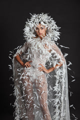 White tulle strapless gown worn with a hooded cape, hand appliquéd with coq plumes and embroidered with metallic silver threads, glass beads and sequins