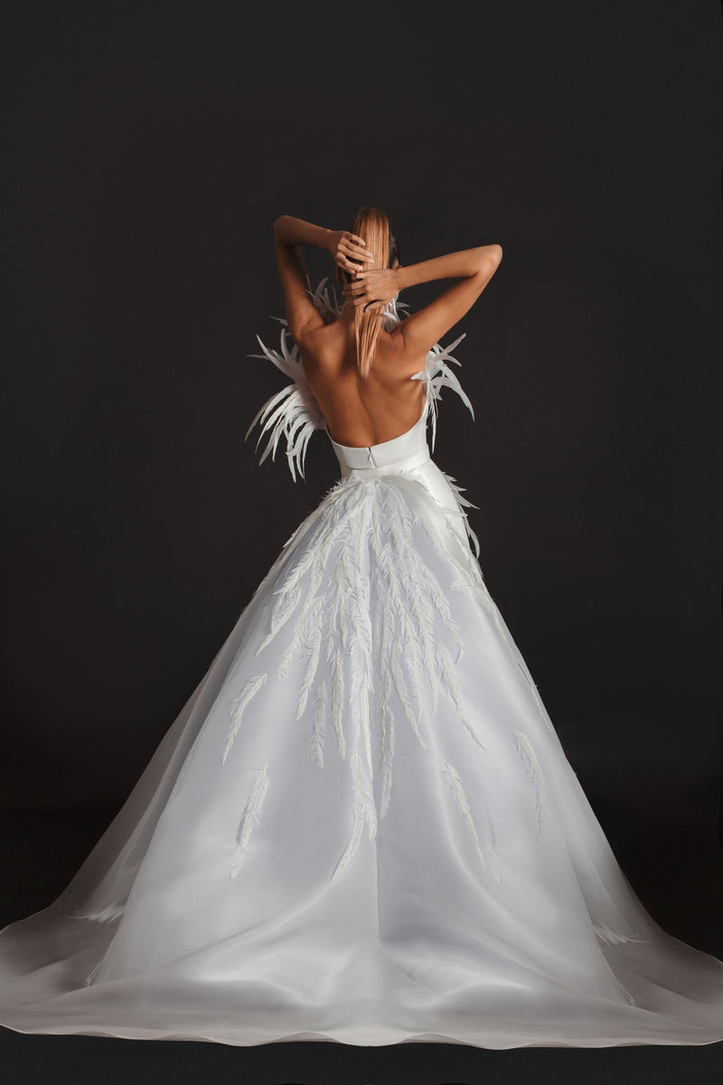 Sleeveless off-white liquid gazaar gown with voluminous floor sweeping overskirt; hand appliquéd with coq plumes and embroidered with Swarovski crystals