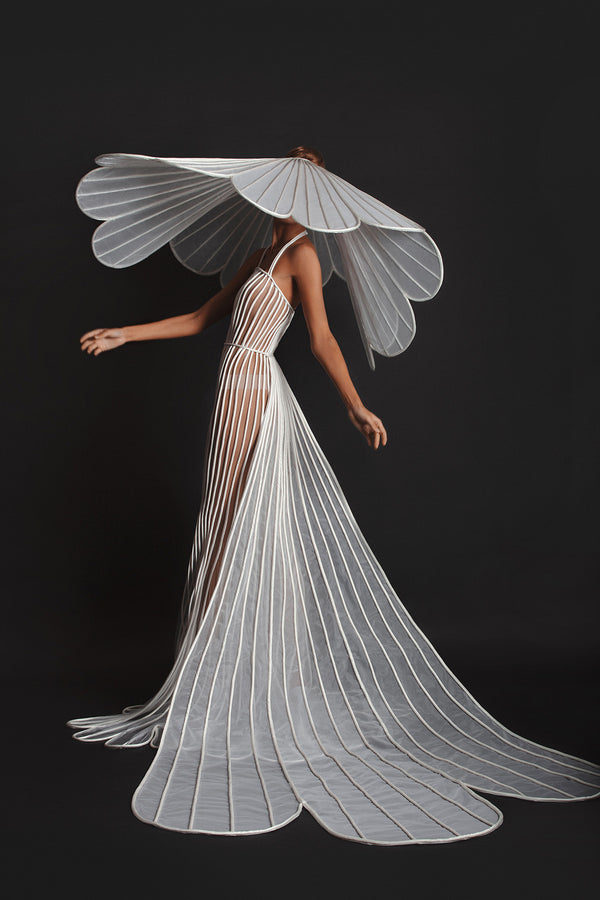 Signature sheer dress in white tulle and silk satin. Worn with a train and a hat crafted in three dimensional tubes