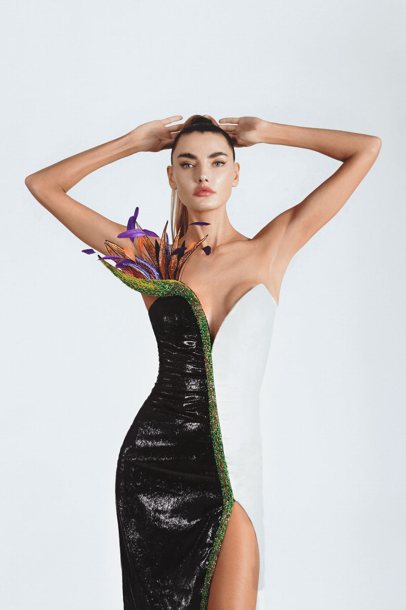 Sleeveless black & white liquid velvet dress with a sweetheart neckline and a thigh high slit, lavishly illustrated with a bird of paradise flower embroidered in 3D silk and metallic threadwork, glass beads, macro sequins, crystals and plumes