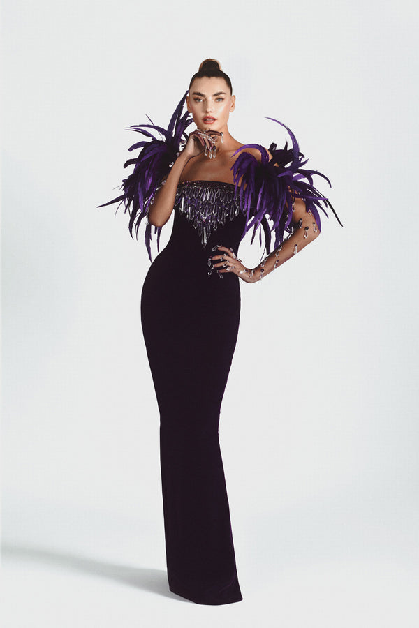 Purple velvet strapless gown, hand embroidered with Swarovski stones, crystal spikes, and finished with coq plumes. Worn with tulle gloves embroidered with stones and dripping crystals