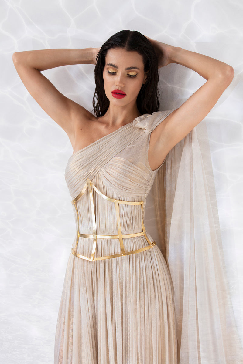One shoulder exquisitely draped asymmetric gown in gold foiled silk tulle, worn with a gold-plated corset handcrafted from solid brass