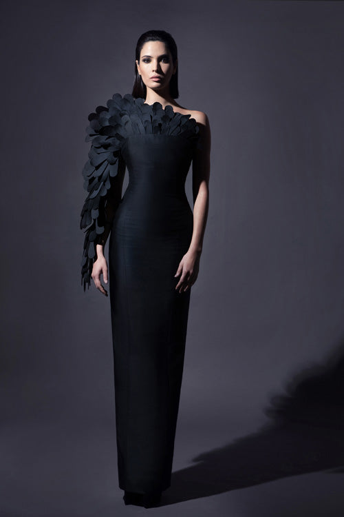 Black zibeline gown with a cluster of laser-cut plumes enveloping the neckline and flowing dramatically down one arm to incarnate a sleeve