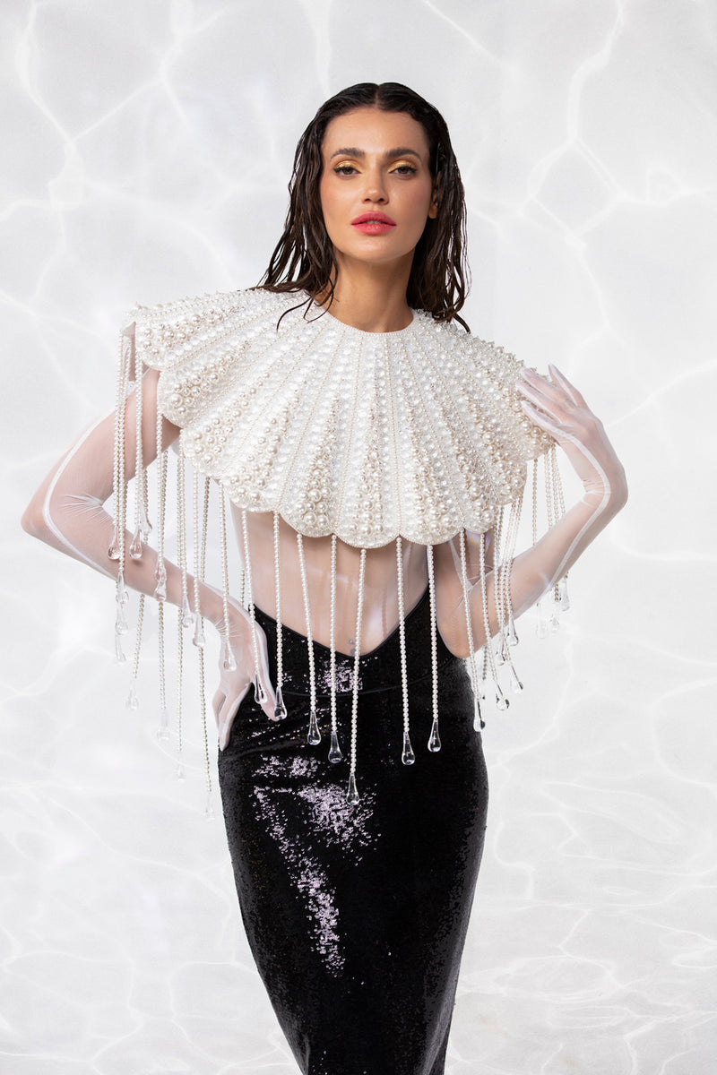 Scallop shell inspired ensemble consisting of a cropped top embroidered with pearls, crystals, and hand blown glass drops. Worn with a white sheer bodysuit and a pencil skirt in high gloss sequins
